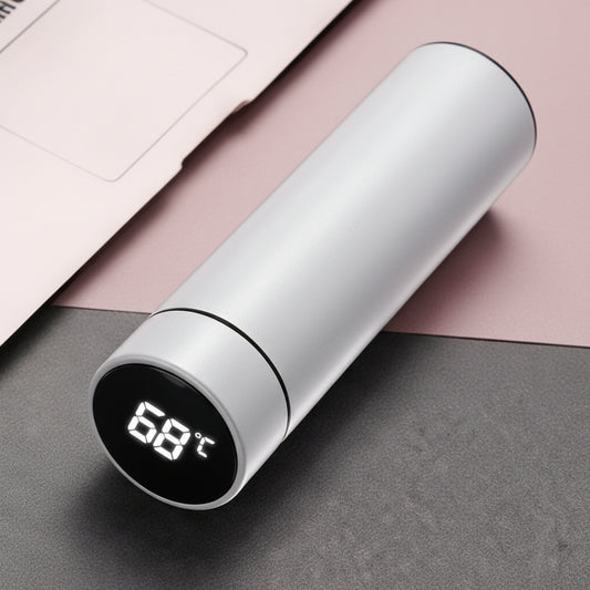 White smart thermos bottle on office desk with laptop.